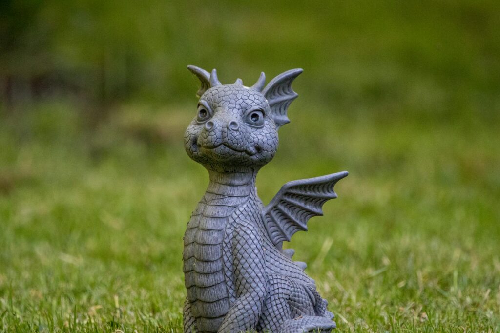 A cute dragon statue sits on vibrant green grass, crafted with intricate detail.